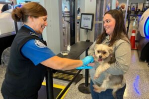 mujer cargando a su perro en el aeropuerto