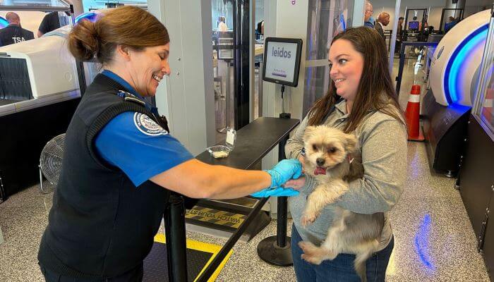 mujer cargando a su perro en el aeropuerto